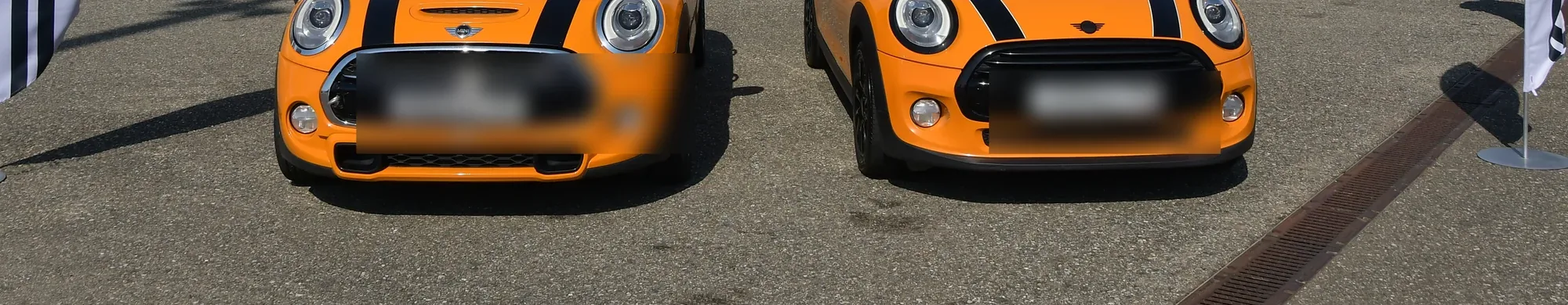 Два оранжевых Mini стоят рядом, вокруг машины клуба